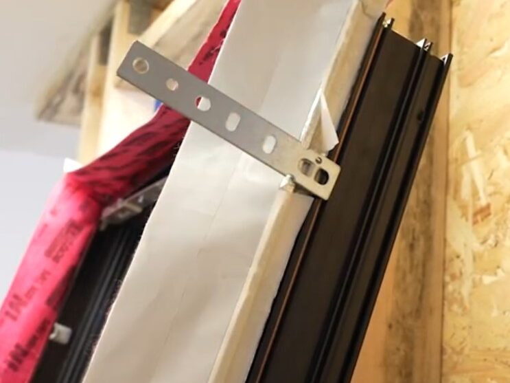 placing strap anchors into the window frame